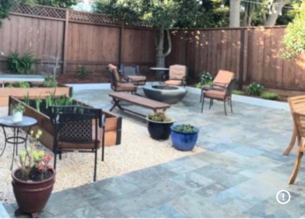 Stone tile patio with concrete fire pit, lounge chairs and raised planter beds