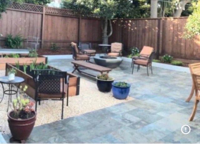 Stone tile patio with concrete fire pit, lounge chairs and raised planter beds