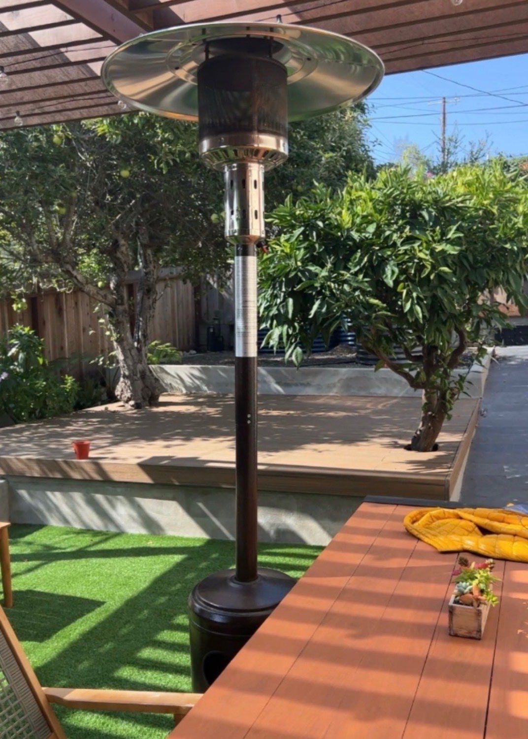 Covered pergola dining area with patio heater, composite decking and mature citrus trees