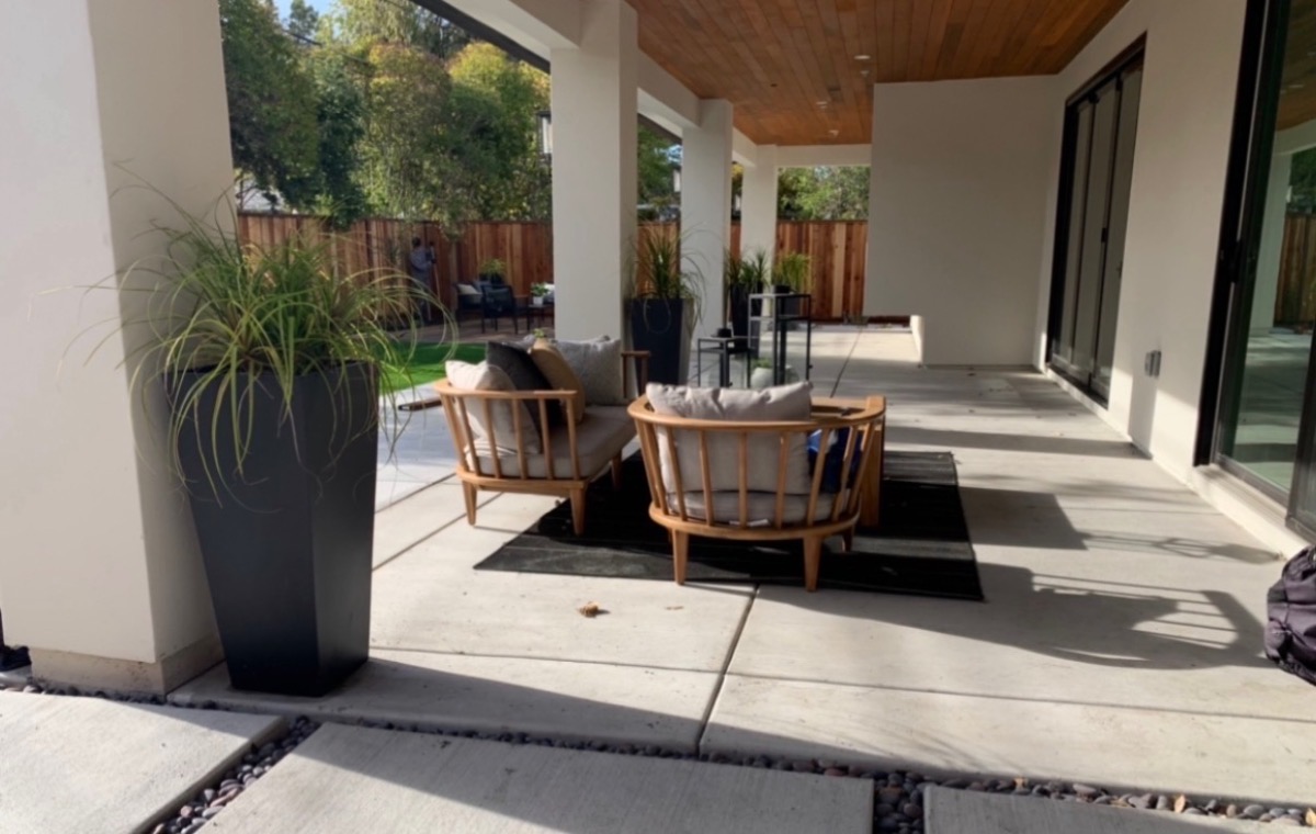 Contemporary covered patio with natural wood ceiling, concrete pavers, ornamental grasses and lounge chairs