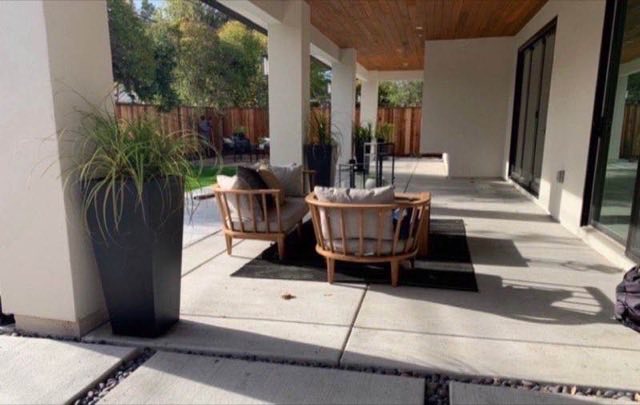 Contemporary covered patio with natural wood ceiling, concrete pavers, ornamental grasses and lounge chairs