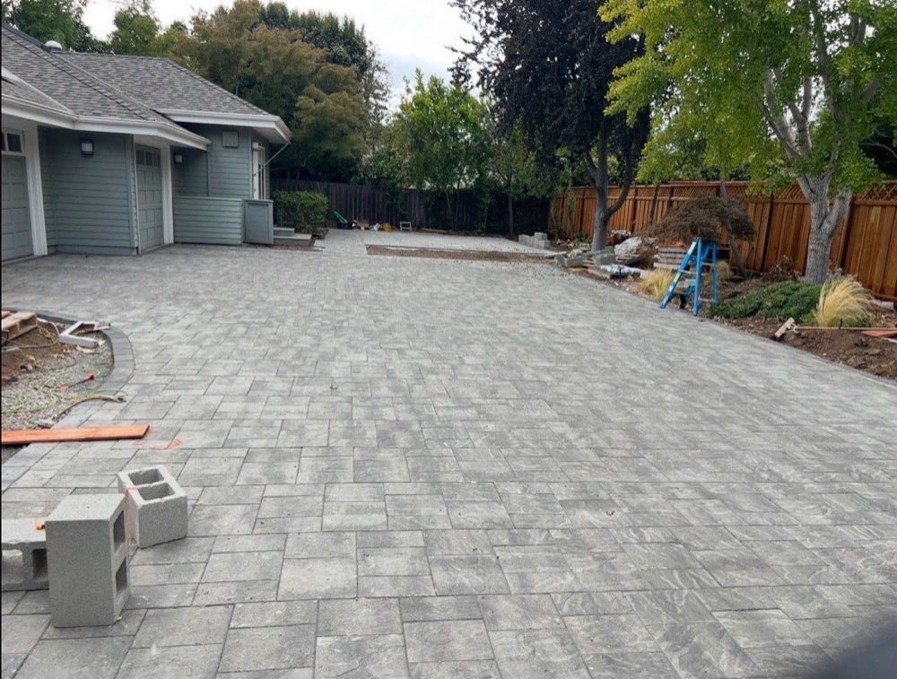 Garden renovation project: large interlocking paver patio installation beside craftsman-style home