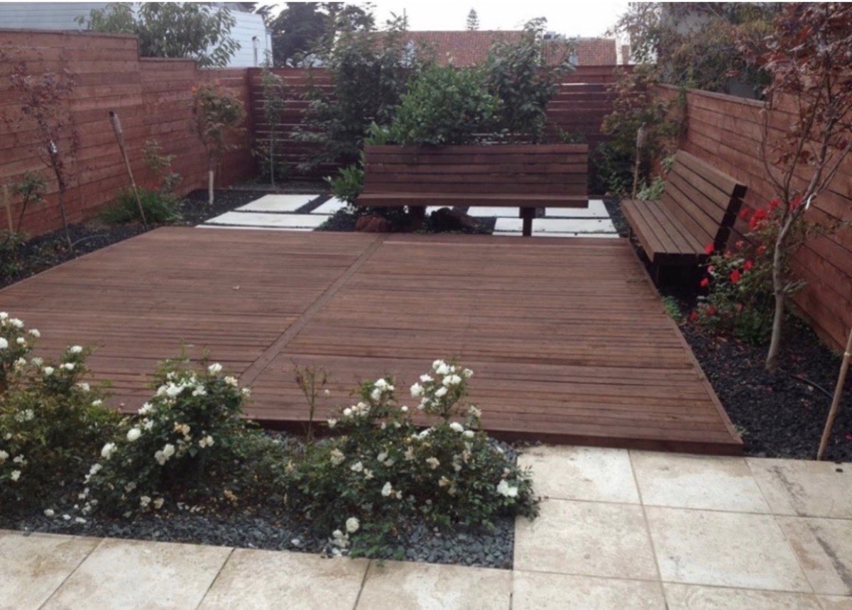 Modern backyard with raised hardwood deck, built-in bench seating, planters and cedar privacy fencing
