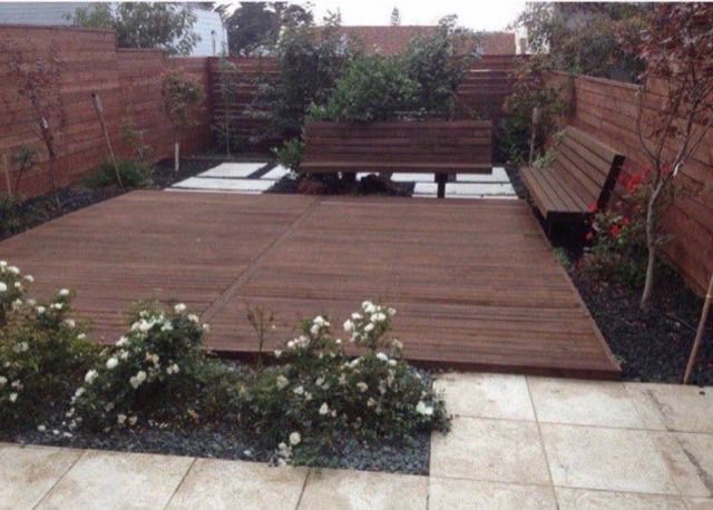 Modern backyard with raised hardwood deck, built-in bench seating, planters and cedar privacy fencing