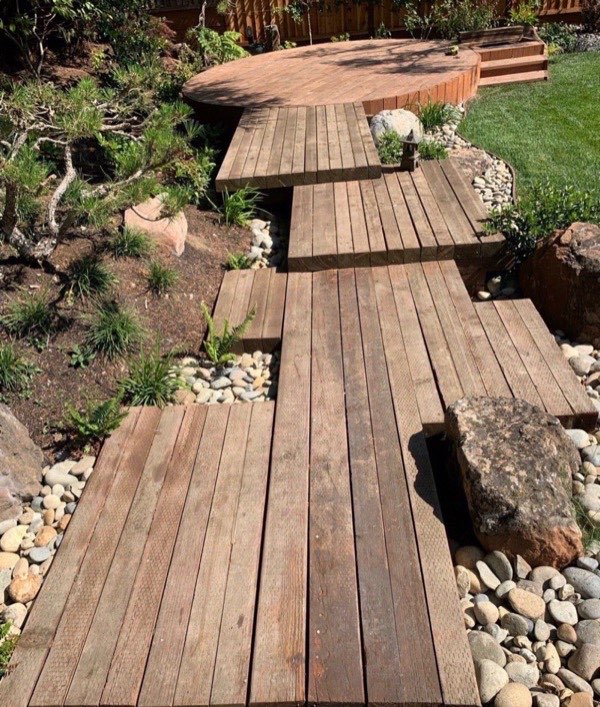 Floating timber deck walkway with river rock dry creek beds and ornamental grasses