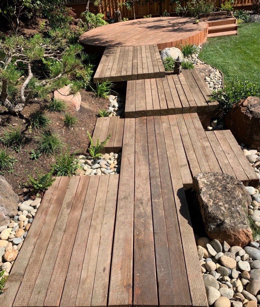 Floating timber deck walkway with staggered platforms, river rock dry creek beds, boulders and ornamental grasses